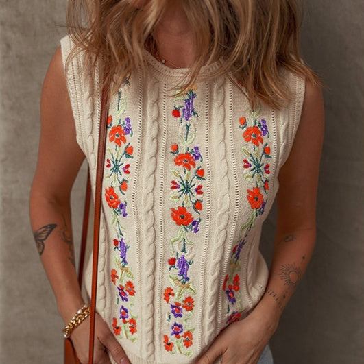 Femme portant un gilet tricoté écru sans manches avec broderies florales colorées – style rétro tendance disponible chez Luxorel