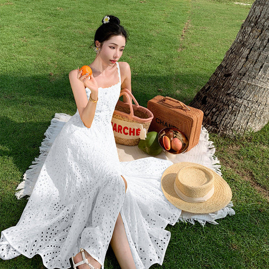 Femme portant une robe d’été blanche à bretelles fines, cintrée à la taille avec jupe fluide – tenue plage féminine et légère disponible chez Luxorel