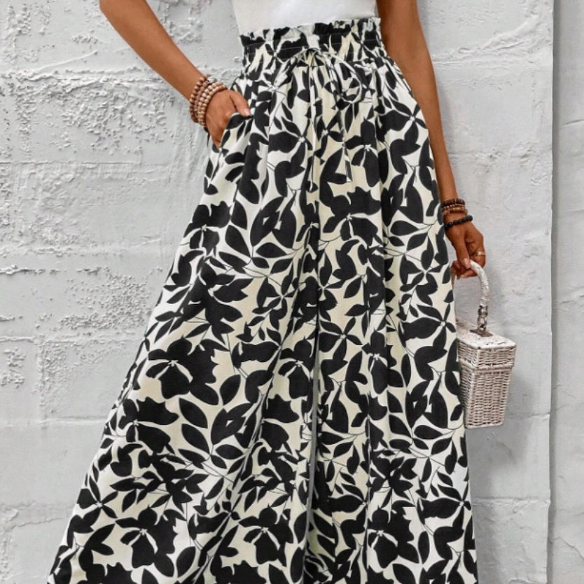 Femme portant un pantalon large à motifs floraux noir et blanc, coupe fluide et taille haute – style bohème chic signé Luxorel