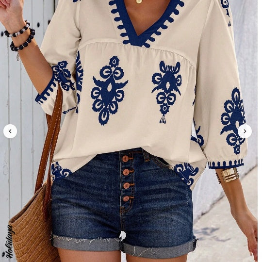 Femme portant un chemisier blanc à col V avec motifs bleus bohèmes et manches courtes – look estival léger et décontracté proposé par Luxorel