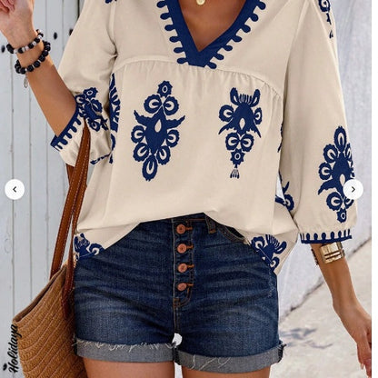 Femme portant un chemisier blanc à col V avec motifs bleus bohèmes et manches courtes – look estival léger et décontracté proposé par Luxorel