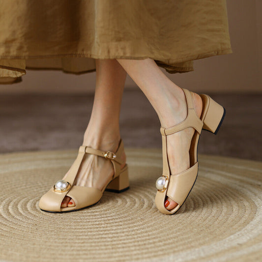 Femme portant des sandales rétro à petit talon carré, bride en T avec boucle et bout ouvert – modèle élégant disponible en beige et blanc, chez Beloreva