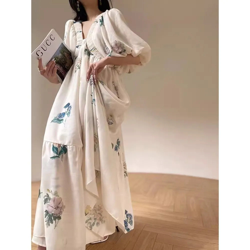 Femme portant une robe longue fluide blanche à fleurs pastel, avec manches bouffantes et coupe ample – modèle bohème et romantique disponible chez Luxorel