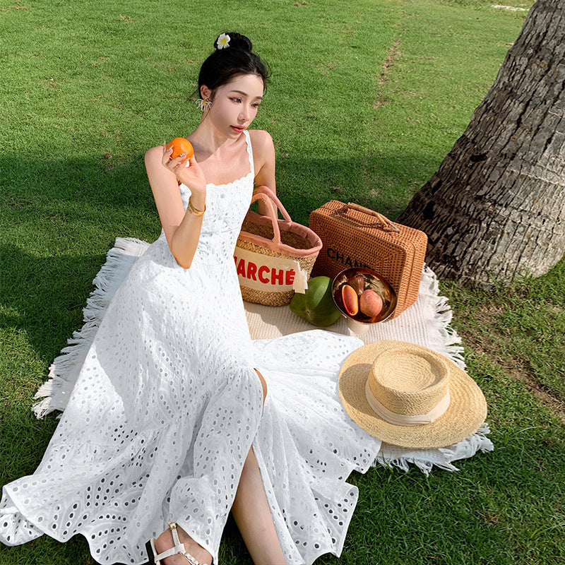 Femme portant une robe d’été blanche à bretelles fines, cintrée à la taille avec jupe fluide – tenue plage féminine et légère disponible chez Luxorel

